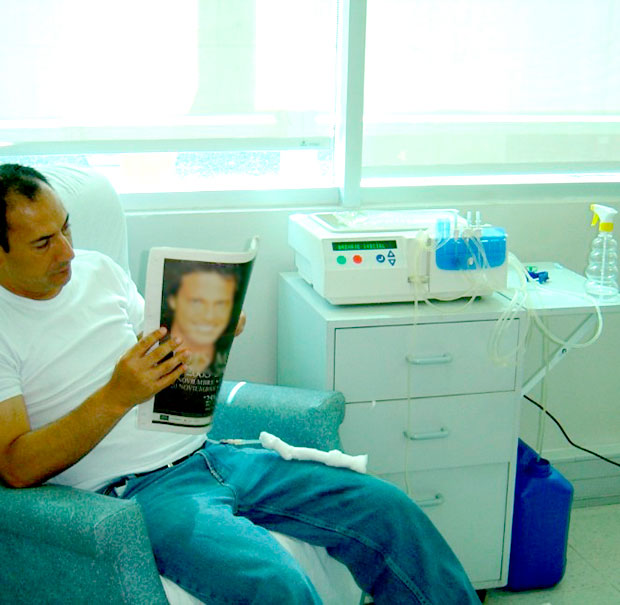 Man sitting going through Continous Ambulatory Peritoneal Dyalisis (CAPD) treatment.