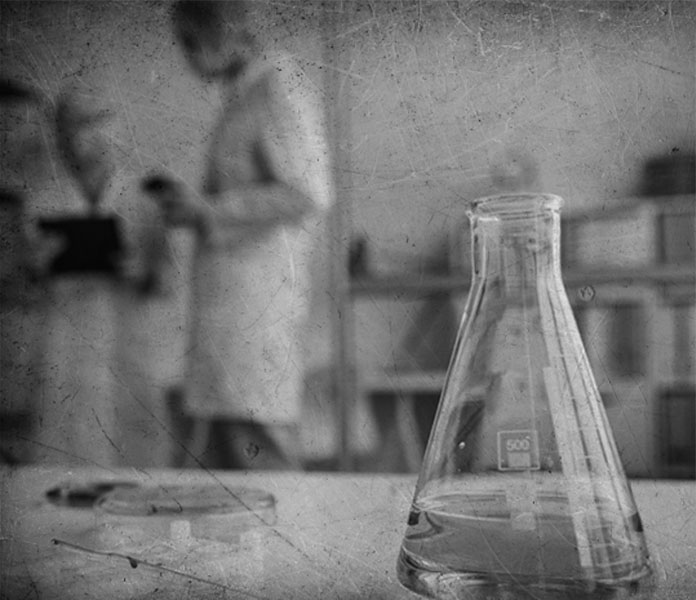 Fotografía en blanco y negro de científicas y científicos realizando experimentos con materiales de laboratorio